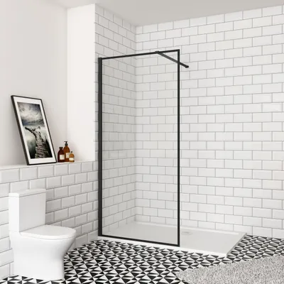 A modern bathroom with white subway tiles, a black and white patterned floor, a white toilet, and a walk-in shower with a black frame and clear glass.