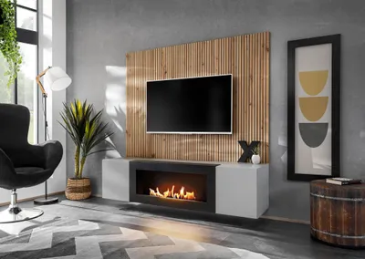 A modern living room with a wall-mounted entertainment unit featuring a TV, a bio-ethanol fireplace, and wooden paneling.