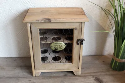 A wooden egg cabinet with a wire mesh door and a small metal plaque.