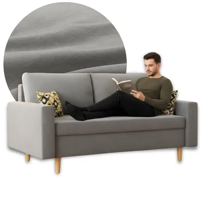 A man is reading a book while sitting on a gray sofa. A close-up of the sofa's fabric is shown in a circle in the upper left corner.