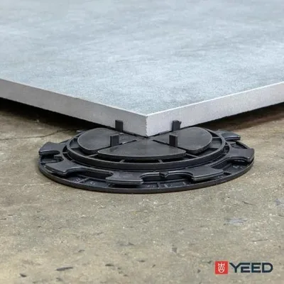 A close-up of a grey tile resting on a black adjustable terrace support.
