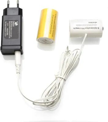A black power adapter, a yellow battery, and a white battery with a white cable are arranged on a white background.