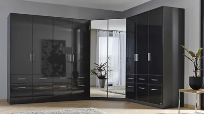 A corner wardrobe with mirrored doors and drawers in a room.
