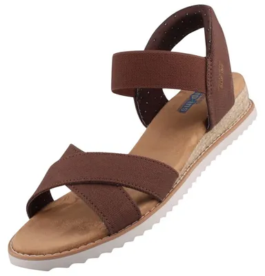Auf dem Bild ist eine braune Sandale zu sehen die von der Seite betrachtet wird. Die Sandale hat ein schlichtes Design mit einem breiten Riemen und einer flexiblen Sohle.