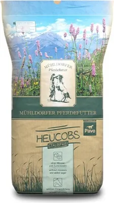 A bag of Mühldorfer Heucobs Staubfrei horse feed, with a scenic mountain and flower landscape on the top portion of the packaging.