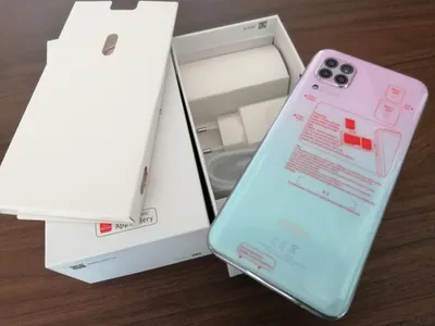 A Huawei P40 Lite smartphone is shown in its packaging, alongside its charger and cables.