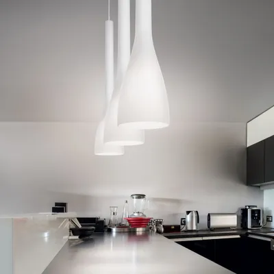 A modern kitchen counter with appliances and three pendant lights hanging above.