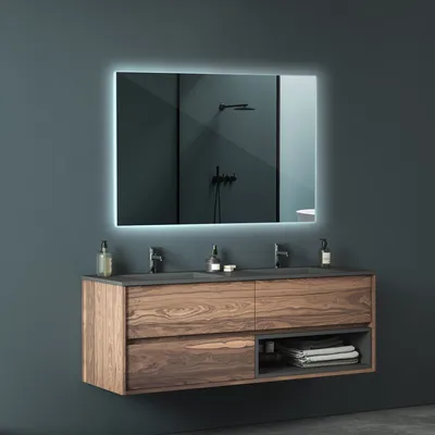 A modern bathroom vanity with a large, illuminated mirror above it.