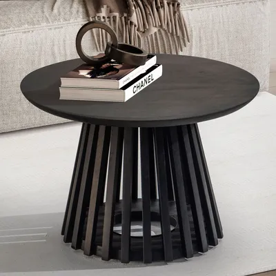 A round, dark wooden coffee table with a slatted base, decorated with two books and a decorative ring.