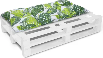 A white wooden pallet with a cushion featuring a green leaf pattern on top, set against a white background.