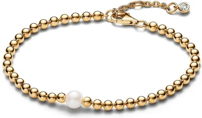 A gold beaded bracelet with a single pearl and a diamond accent at the clasp, displayed on a white background.