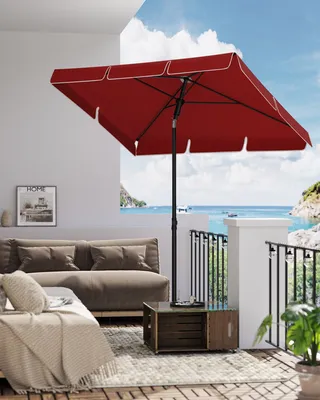 A patio scene with a red umbrella, sofa, and a view of the ocean.