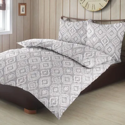 A bed with a gray and white patterned duvet and pillow.