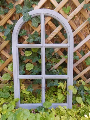 A decorative window frame with a lattice background and ivy growing around it.