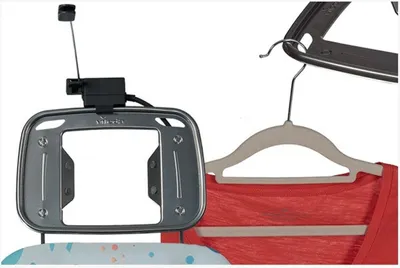 A close-up view of an ironing board attachment and a hanger with a red shirt.