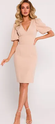 A woman modeling a beige dress against a white background.