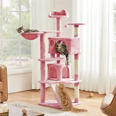Three cats are playing on a pink cat tree in a living room.