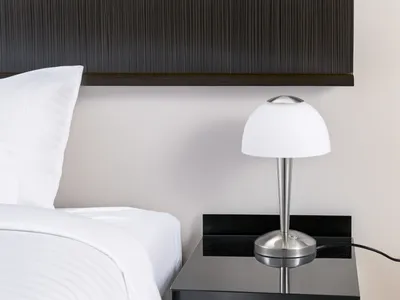 A bedside lamp on a nightstand next to a bed.