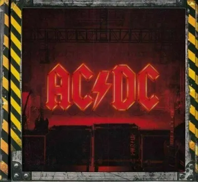 The image shows the AC/DC logo in red neon lights against a dark, stage-like background with concert equipment visible. The sides of the image have a black and yellow hazard stripe border.