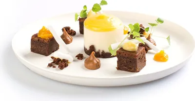 A dessert platter with brownies, cheesecake, and garnishes.