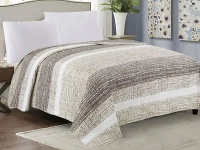 A bed with a striped quilt and white pillows.