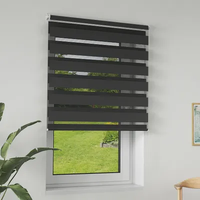 A dark gray zebra blind is installed on a window, partially covering a view of a green lawn and garden.
