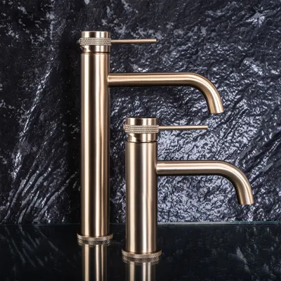 Two gold faucets are displayed against a dark, textured background.
