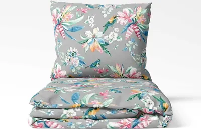 A folded duvet and pillow set with a floral and bird pattern on a light gray background.