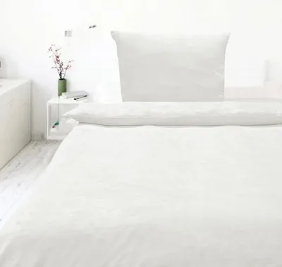 A white bed with a white duvet and pillow.