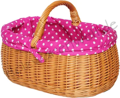 A wicker basket with a pink and white polka dot fabric lining and a woven handle.