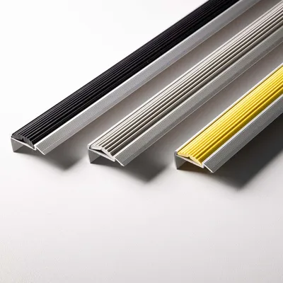 Three stair nosing profiles with different colored rubber inserts are arranged diagonally on a white background.