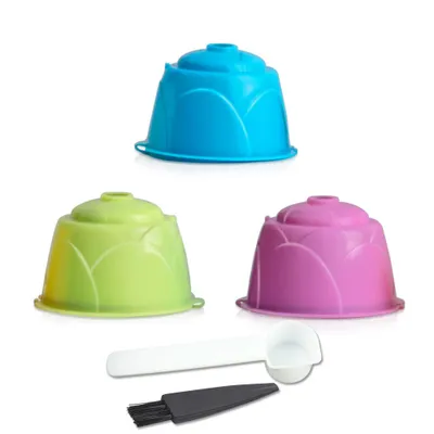 Three reusable coffee capsules in blue, green, and purple, along with a white scoop and a black brush, are displayed against a white background.