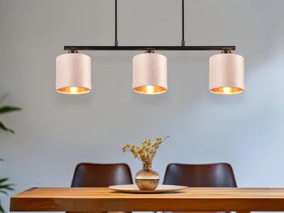 A pendant light fixture with three beige lampshades hangs above a wooden dining table.