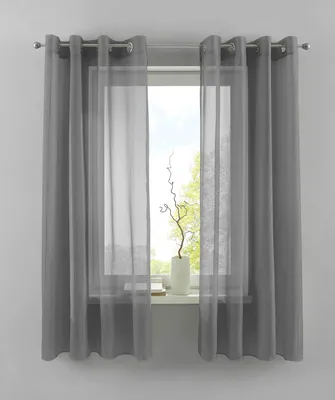 A window with gray curtains and sheer white curtains, showing a vase with a decorative branch on the windowsill.