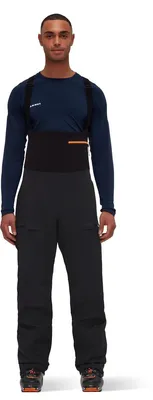Mann trägt die Haldigrat HS Bib Pants Men von Mammut; schwarze Hardshellhose mit Trägern; sportliche Pose.