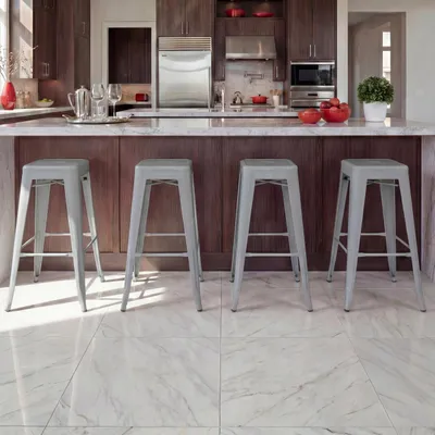 A modern kitchen island with four gray metal bar stools.