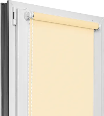 A close-up view of a light yellow roller blind installed on a white window frame.