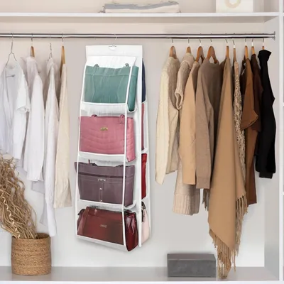 A closet interior with clothing and a hanging organizer for handbags.