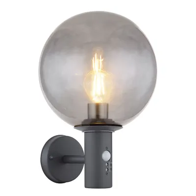 A wall-mounted outdoor light fixture with a spherical, smoky glass shade and a built-in motion sensor.