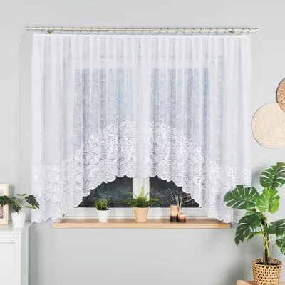 A white lace curtain is displayed in front of a window, with plants and decorative items on the windowsill.