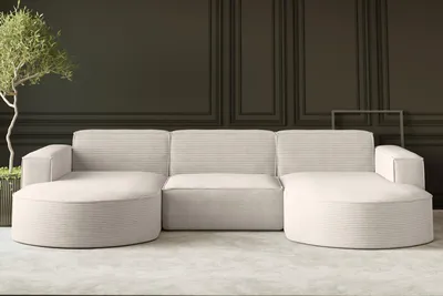 A modern, beige sectional sofa is shown in a minimalist living room setting.