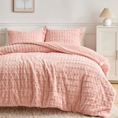 A close-up view of a pink plush duvet cover and pillowcases on a bed.