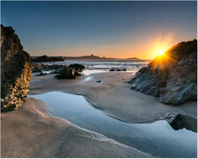 Produktbild von Wallario Poster - Sonnenuntergang hinter einem Felsen am Strand, Kunstdruck Größe: 40 x 50 cm