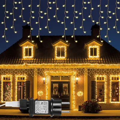 A house decorated with warm white icicle lights at night.