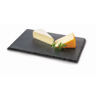 Two wedges of cheese and a sprig of parsley are presented on a dark slate serving board against a white background.