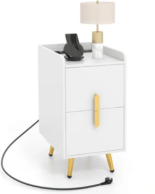 A white nightstand with gold accents, featuring two drawers and a lamp and wireless charger on top.