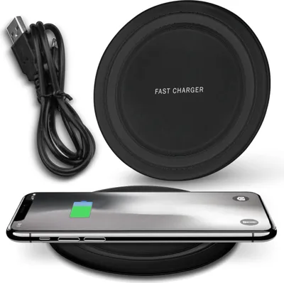A black wireless charging pad with a USB cable and a smartphone charging on it.