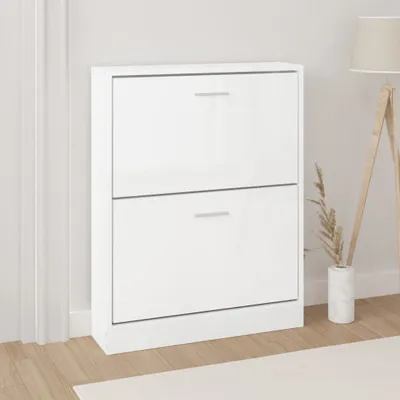 A white shoe cabinet with two drawers is shown in a room, next to a wall and a floor lamp.