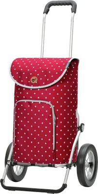 A red and white polka dot shopping trolley with large wheels and a black handle, isolated on a white background.
