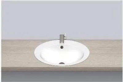 A white oval sink with a silver faucet is installed on a light brown countertop against a light gray wall.